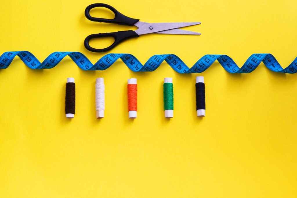 Sewing tools including scissors, measuring tape, and colorful thread spools.